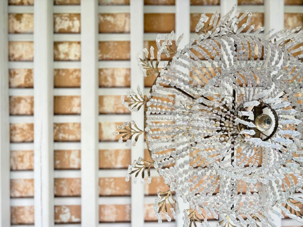Fotografía del interior de una casa Palacio, en la Plaza de Candelaria uno de los Mejores lugares para visitar en Cádiz. La imagen muestra un arco de piedra ostionera y una lampara de araña de estilo clásico y el techo de vigas de madera vistas.