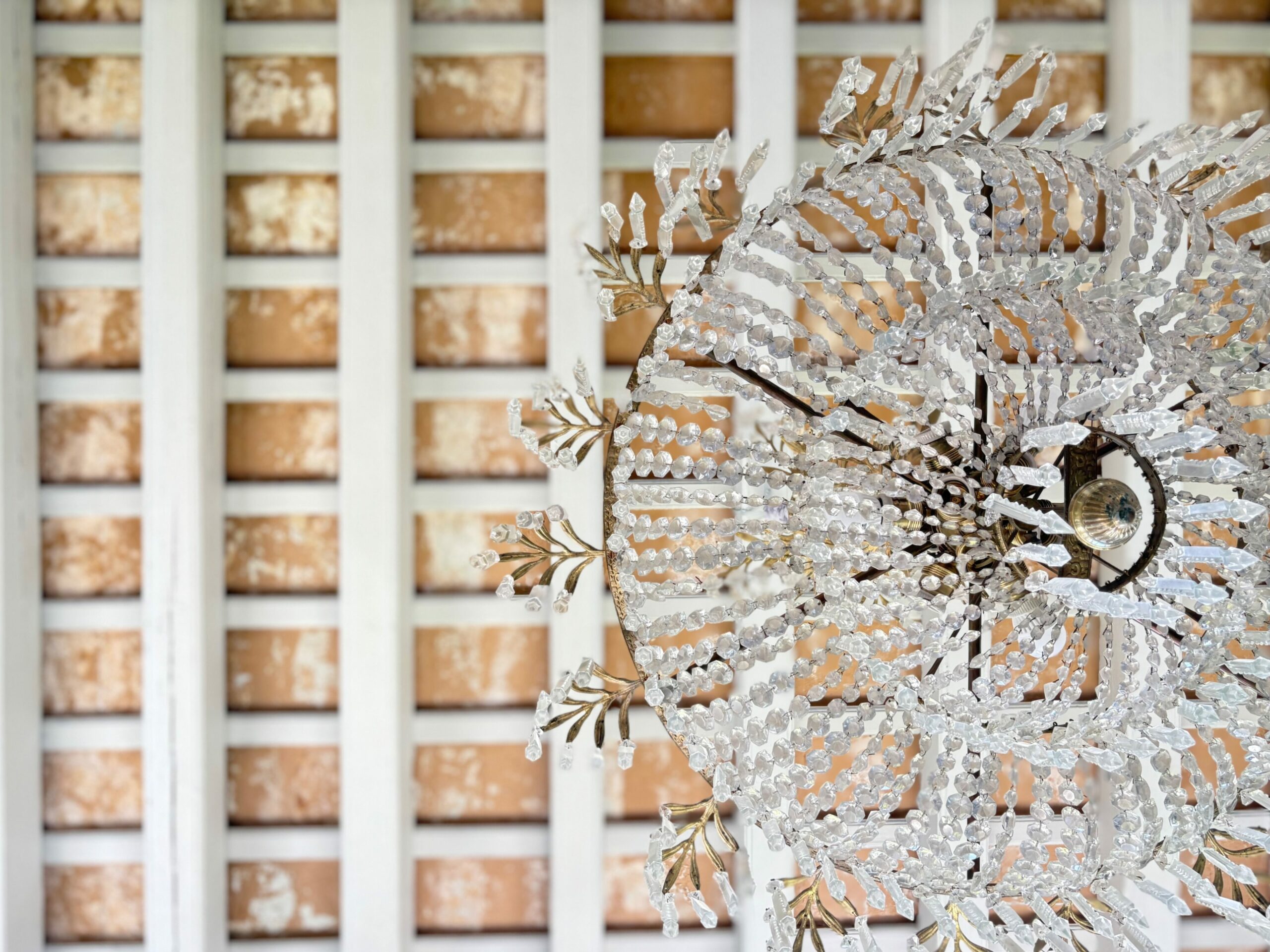 Fotografía del interior de una casa Palacio, en la Plaza de Candelaria uno de los Mejores lugares para visitar en Cádiz. La imagen muestra un arco de piedra ostionera y una lampara de araña de estilo clásico y el techo de vigas de madera vistas.