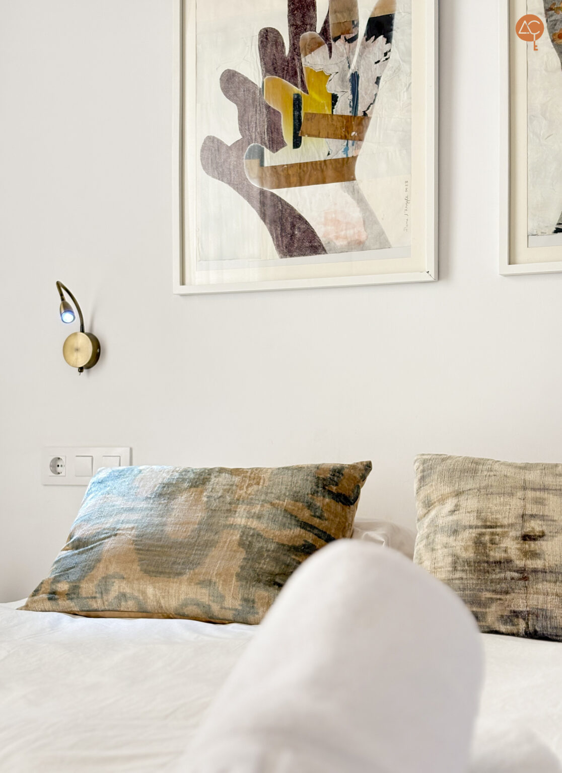 cama en primer plano con cojines y cuadros