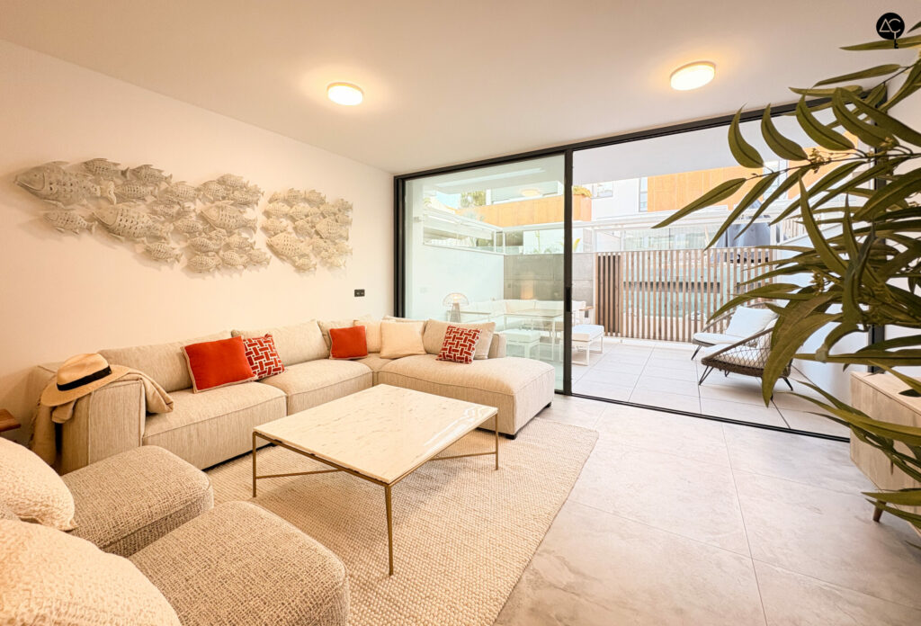 Salón con apertura a terraza a través de gran muro de cristal, ambiente cálido y acogedor