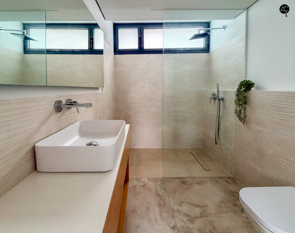 Vista lateral de un baño con ducha y mampara de cristal