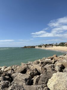 playa con muralla y orilla, piedras en primer plano